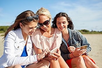 summer vacation, holidays, technology, travel and people concept - group of happy young women with smartphones on beach