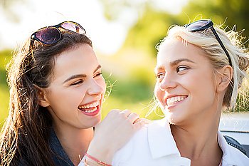 summer vacation, holidays, friendship and people concept - happy young women or teenage girls laughing outdoors