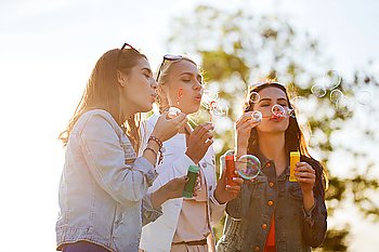 summer vacation, holidays, fun and people concept - group of happy young women or teenage girls blowing bubbles outdoors