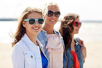 summer vacation, holidays, travel and people concept - group of smiling young women in sunglasses and casual clothes on beach