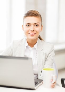 picture of smiling businesswoman with laptop in office