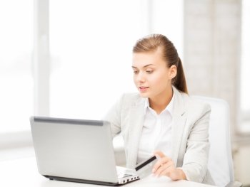 smiling businesswoman with laptop using credit card