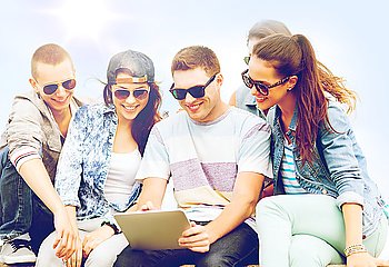 summer holidays, teenage and technology concept - group of teenagers looking at tablet pc