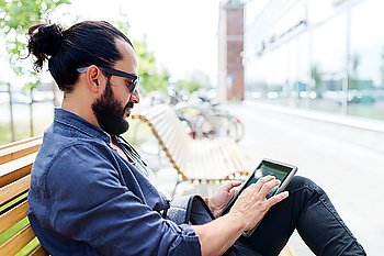 leisure, technology, communication and people concept - man with tablet pc computer sitting on city street bench