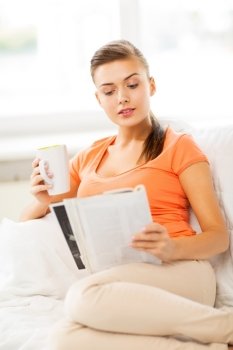 smiling woman with cup of coffee reading magazine at home