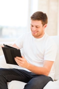 technology and lifestyle concept - handsome man working with tablet pc at home