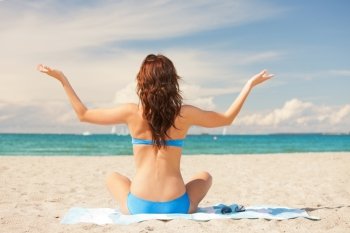 picture of woman practicing yoga lotus pose on the beach.