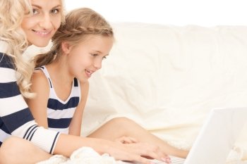 bright picture of happy mother and child with laptop computer (focus on girl)
