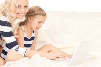 bright picture of happy mother and child with laptop computer (focus on girl)