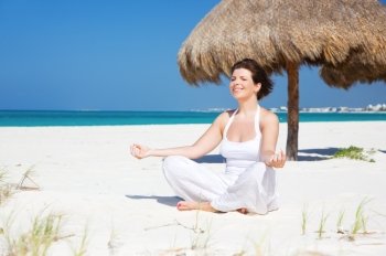 meditation of happy woman in lotus pose on the beach