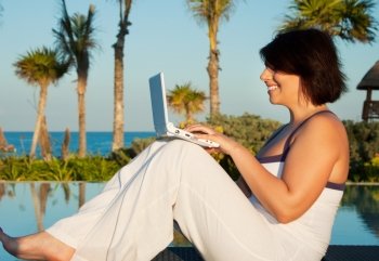 evening light picture of woman with laptop computer at tropical resort