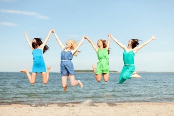summer holidays and vacation concept - smiling girls jumping on the beach