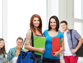 education, school and people concept - two smiling students with bag and folders standing