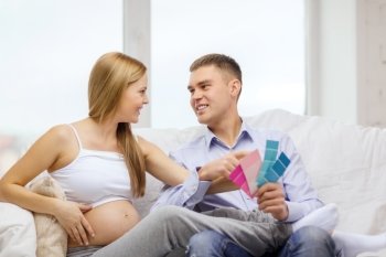 parenthood, renovation and pregnancy concept - smiling expecting parents choosing color for nursery