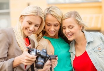 holidays, technology and tourism concept - beautiful blonde women with digital camera in the city