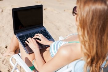 summer holidays, vacation, technology and internet - girl looking at laptop on the beach chair