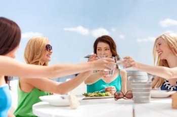 summer holidays and vacation concept - girls making a toast in cafe on the beach