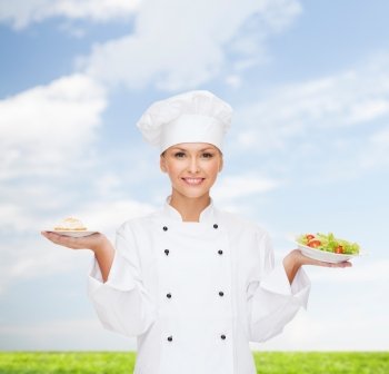cooking and food concept - smiling female chef, cook or baker with salad and cake on plates