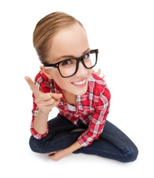 happiness and gesture concept - smiling teenager in eyeglasses with finger up