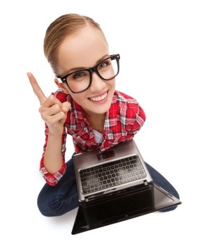 education, technology and internet concept - smiling teenage girl in black eyeglasses with laptop computer