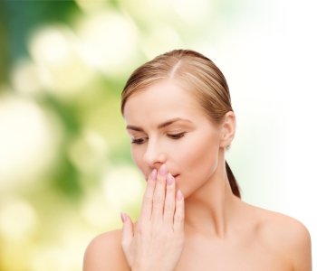 health and beauty concept - clean face of beautiful young woman covering her mouth with hand