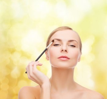 cosmetics, health and beauty concept - beautiful woman with makeup brush
