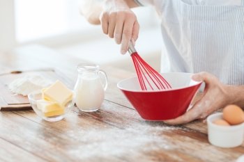 cooking and home concept - close up of male hand whisking something in a bowl