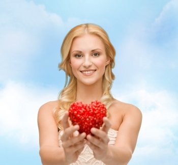 health, charity and love concept - smiling woman giving small red heart