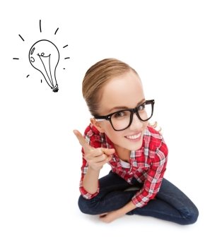 happiness and gesture concept - smiling teenager in eyeglasses with finger up and light bulb