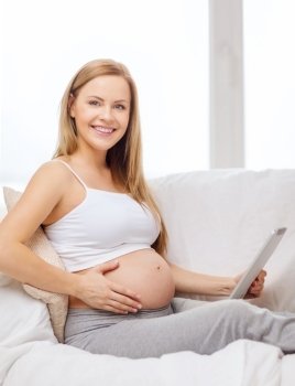 pregnancy, motherhood, internet and technology concept - smiling pregnant woman sitting on sofa with tablet pc computer