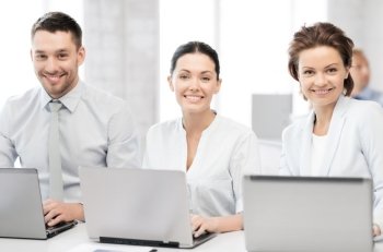 picture of group of people working with laptops in office
