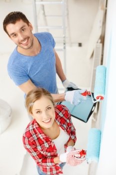 repair, building and home concept - smiling couple painting wall at home