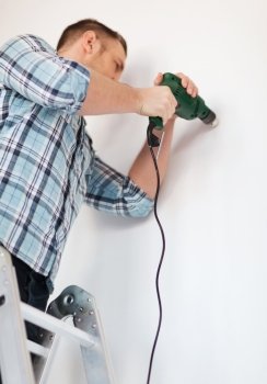 repair, building and home concept - close up of male with electric drill making hole in wall