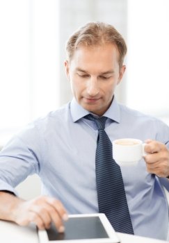 smiling businessman with tablet pc drinking coffee in office