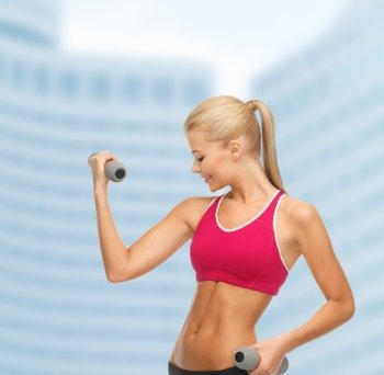 fitness and gym concept - young sporty woman with light dumbbells