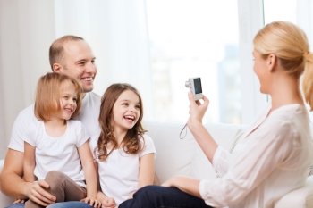 family, children, photography and home concept - smiling happy mother taking picture of father and two daughter at home