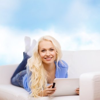 home, technology and internet concept - smiling woman lying on the couch with tablet pc computer