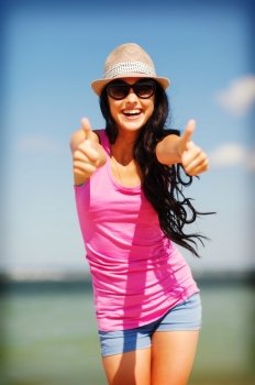summer holidays and vacation - girl showing thumbs up on the beach