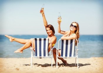summer holidays and vacation - girls sunbathing and drinking on the beach chairs