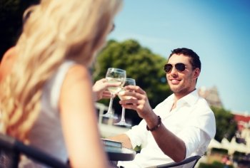 summer holidays and dating concept - man drinking wine with woman in cafe in the city