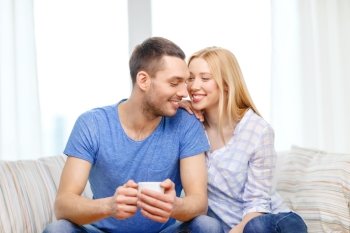 love, family, healthy food and happiness concept - smiling man with cup of tea or coffee with wife or girlfriend at home