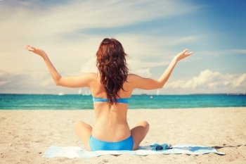picture of woman practicing yoga lotus pose on the beach