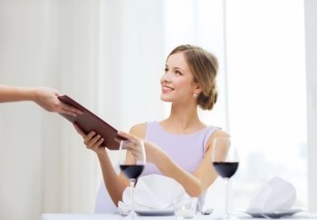 reastaurant and happiness concept - smiling young woman giving menu to waiter at restaurant
