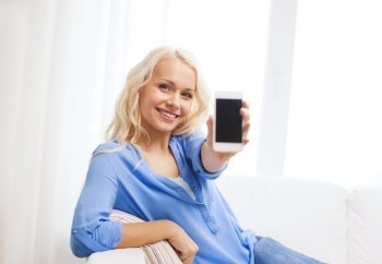home, technology, advertising and internet concept - smiling woman with blank smartphone screen sitting on couch at home