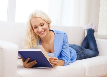 leasure and home concept - smiling middle-aged woman reading book and lying on couch at home