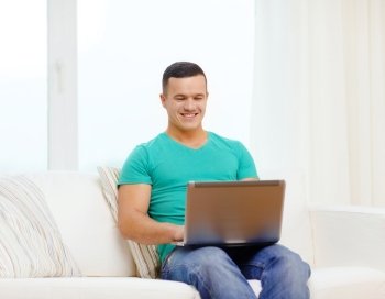 technology, home and lifestyle concept - smiling man working with laptop at home