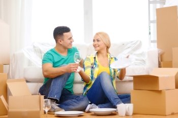 moving, home and couple concept - smiling couple unpaking boxes with kitchenware in new home
