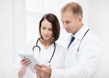 healthcare and medical and technology concept - two doctors looking at tablet pc