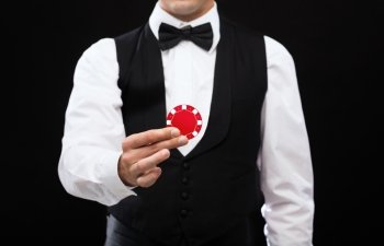 magic, performance, circus, casino and show concept - casino dealer holding red pocker chip