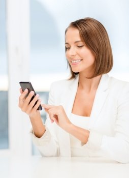 business, technology and internet concept - smiling businesswoman browsing in smartphone in office